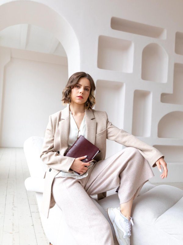 a-young-woman-coach-sits-on-the-white-armchair-with-business-dairy-qact8g02eo6s3k2r3v4q9avv89k63rd4ek3cyl5hkw